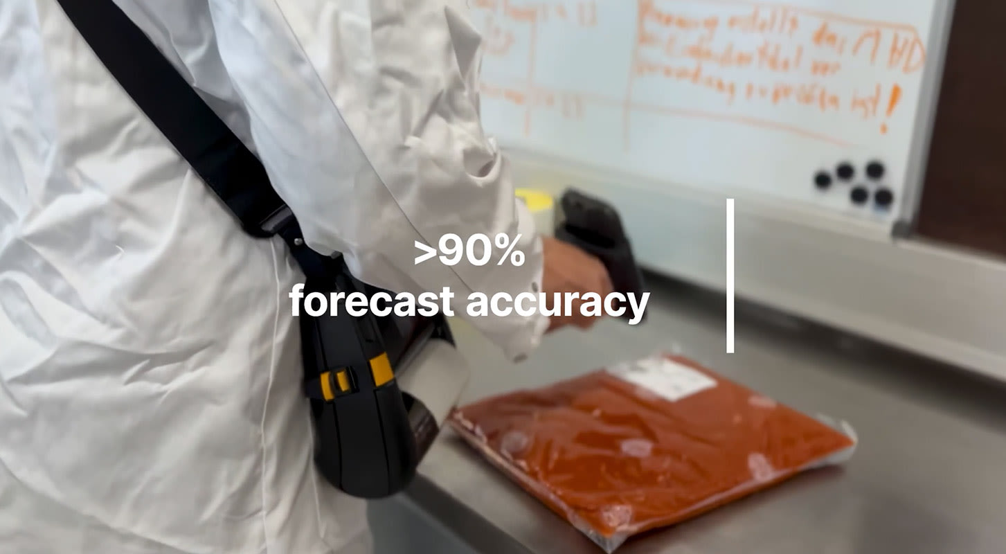 A person in a lab coat scans the barcode on a bag of food, highlighting inventory management.
